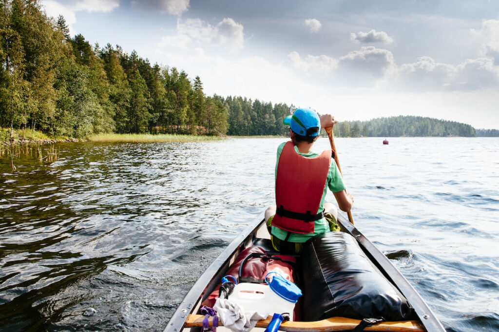 boy paddling in a canoe through Lake Saimaa