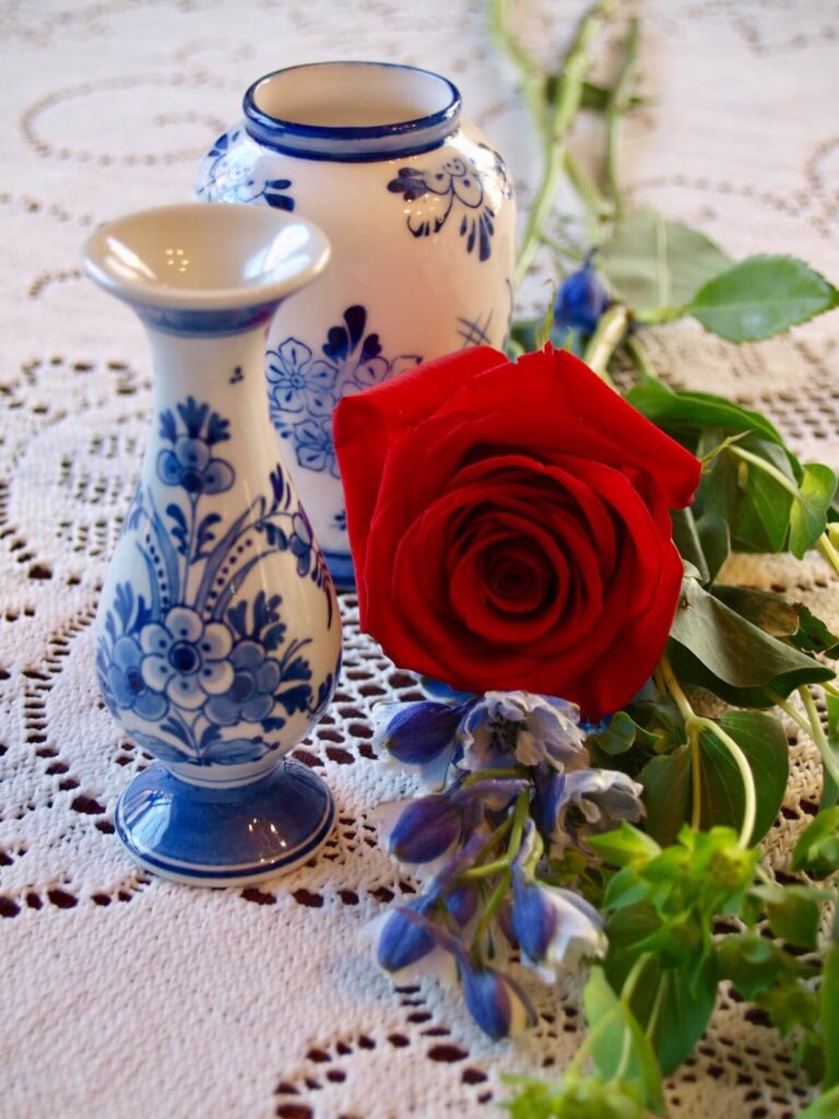 Delft Blue vases and a rose on top of a laced table