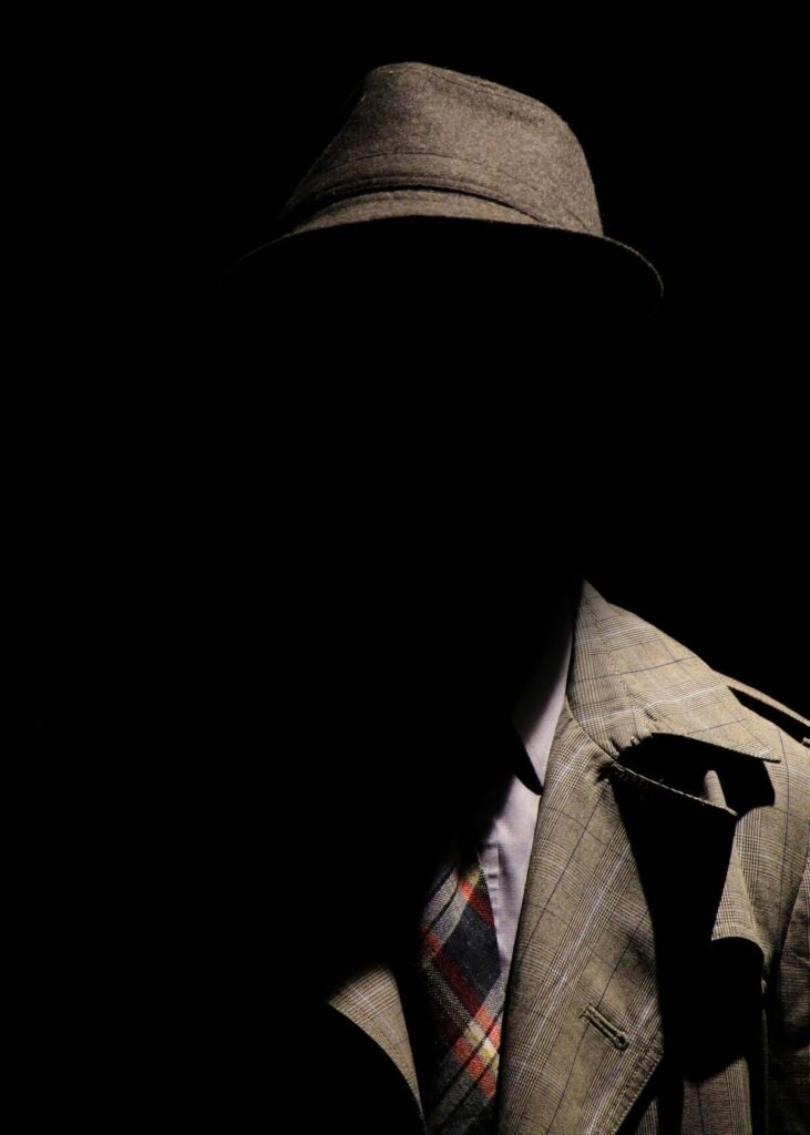 man wearing suit and hat, in the dark
