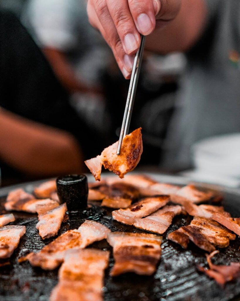 person using chopsticks to grab samgyeopsal