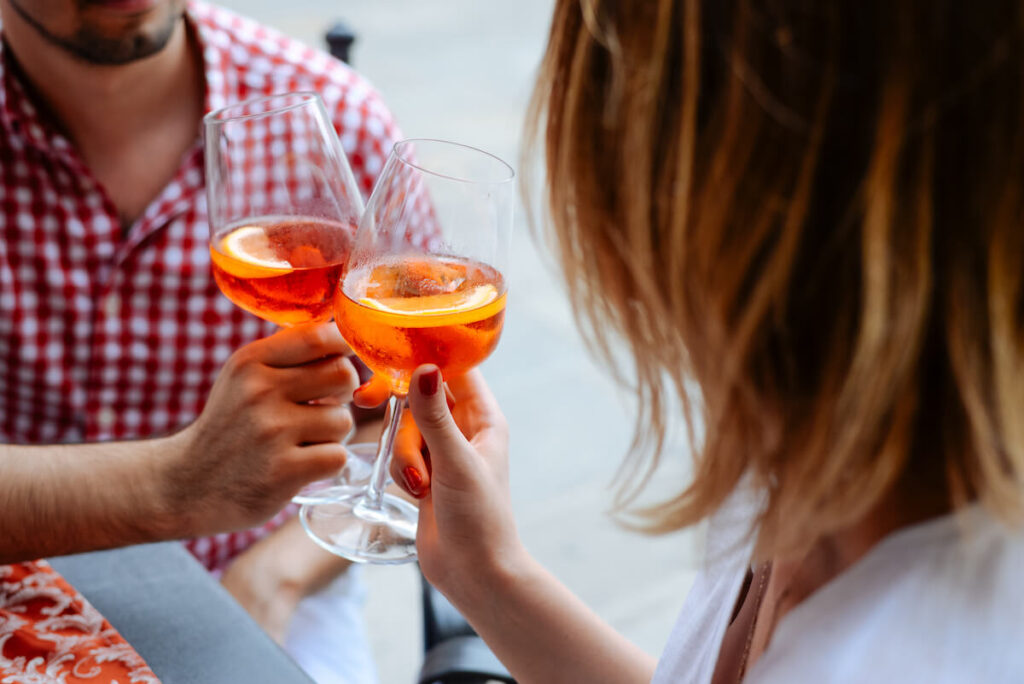A loving couple drinks apelol spritz in Italy, hands with glasses close-up