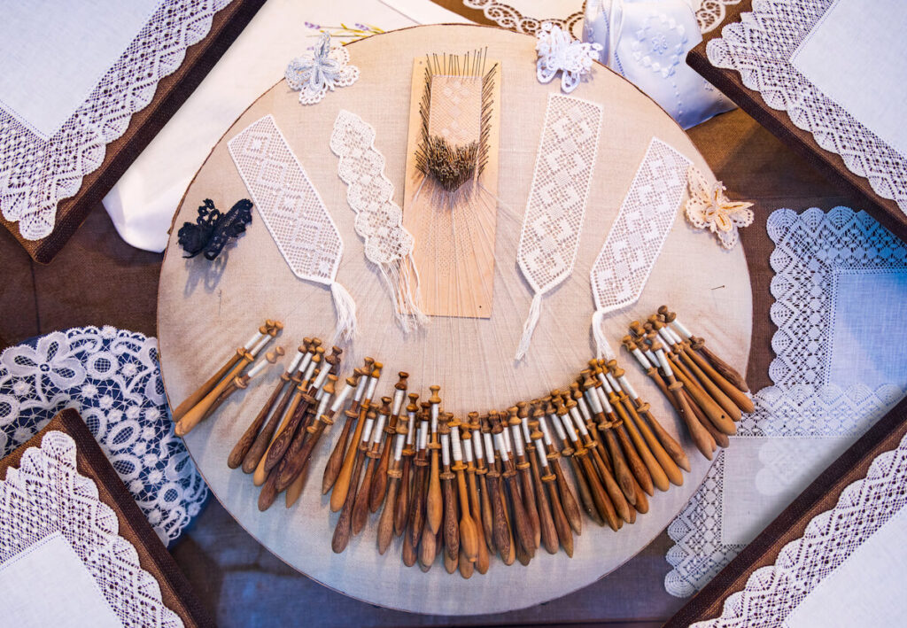 Storefront displaying various Belgian lace styles and samples and bobbins