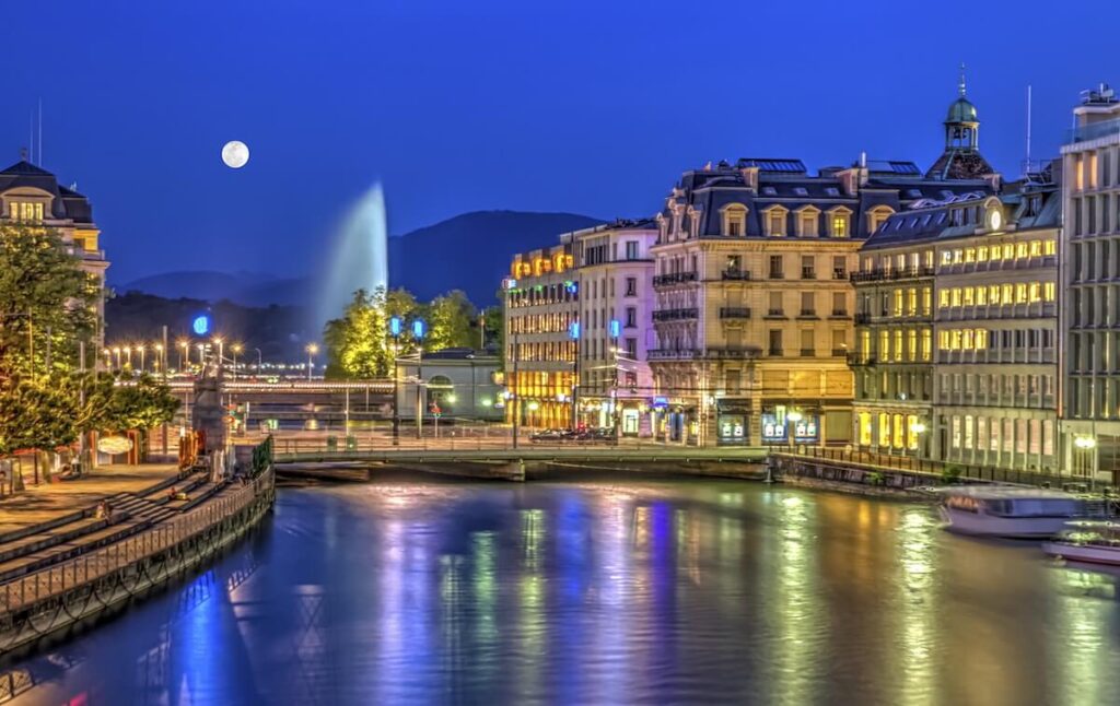Urban view with famous fountain by night with full moon, Geneva