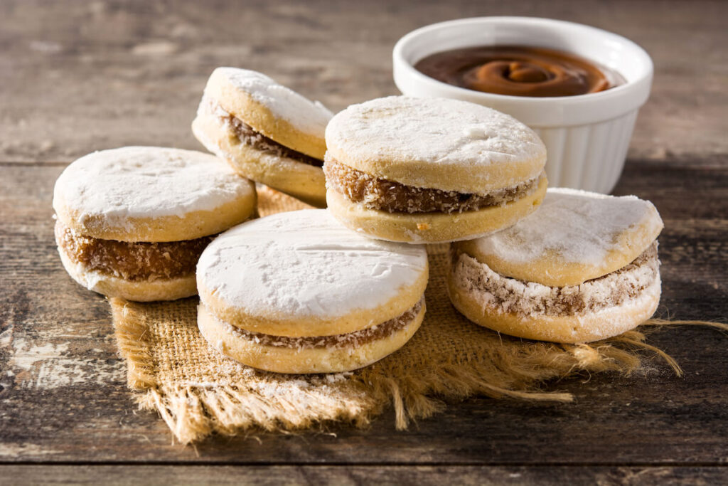 Traditional Argentinian alfajores with dulce de leche and sugar on wooden table