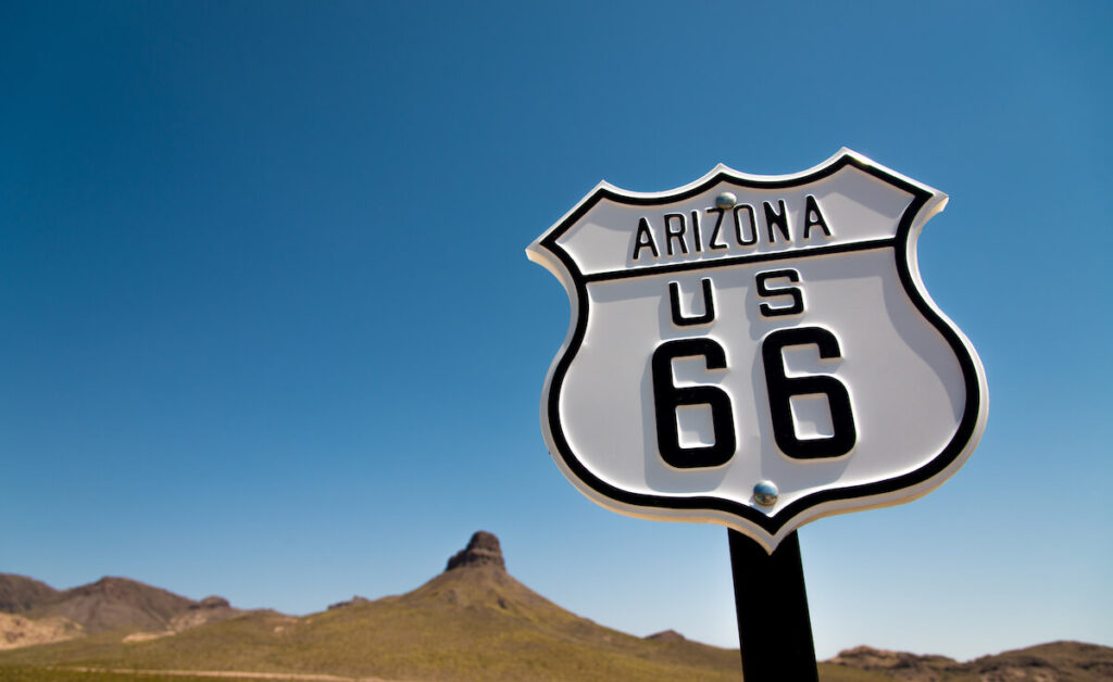A scenic view of a historic Route 66 sign with a sky blue background