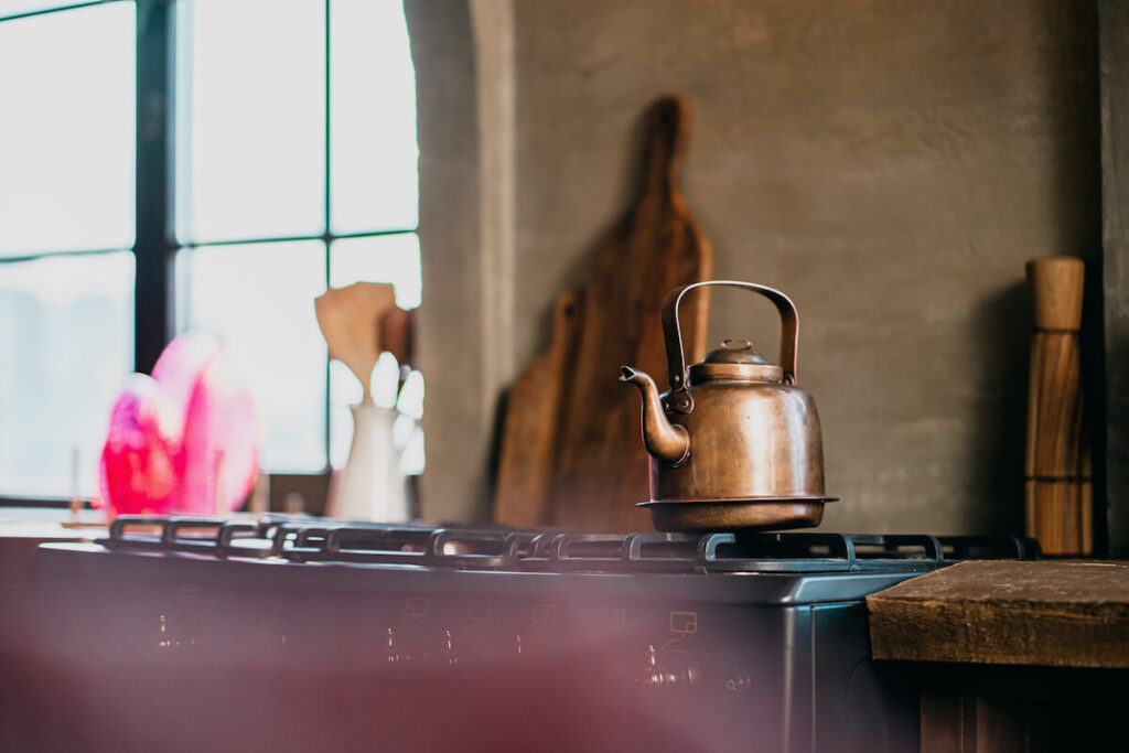 a teapot made of metal steel copper stands on a vintage gas stove