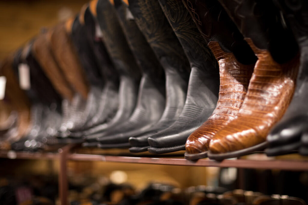 pair of brown alligator leather cowboy boots, on a row of other boots