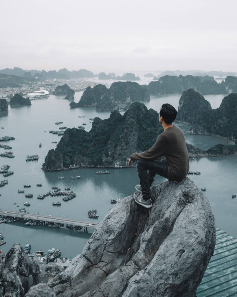 man on top of a rock in ha long bay vietnam