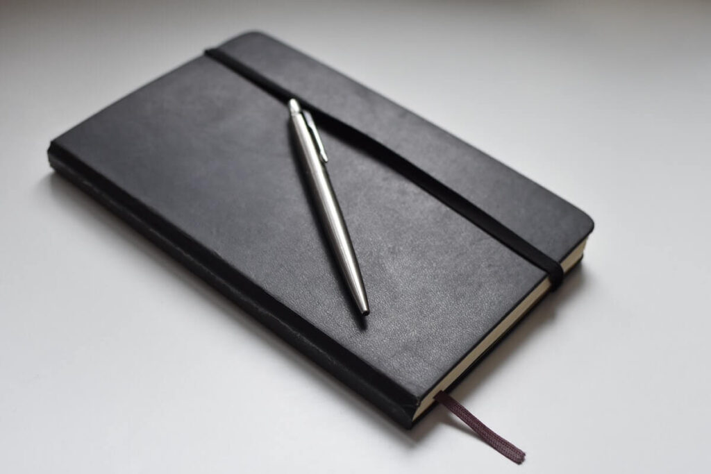 black moleskine notebook with silver pen
