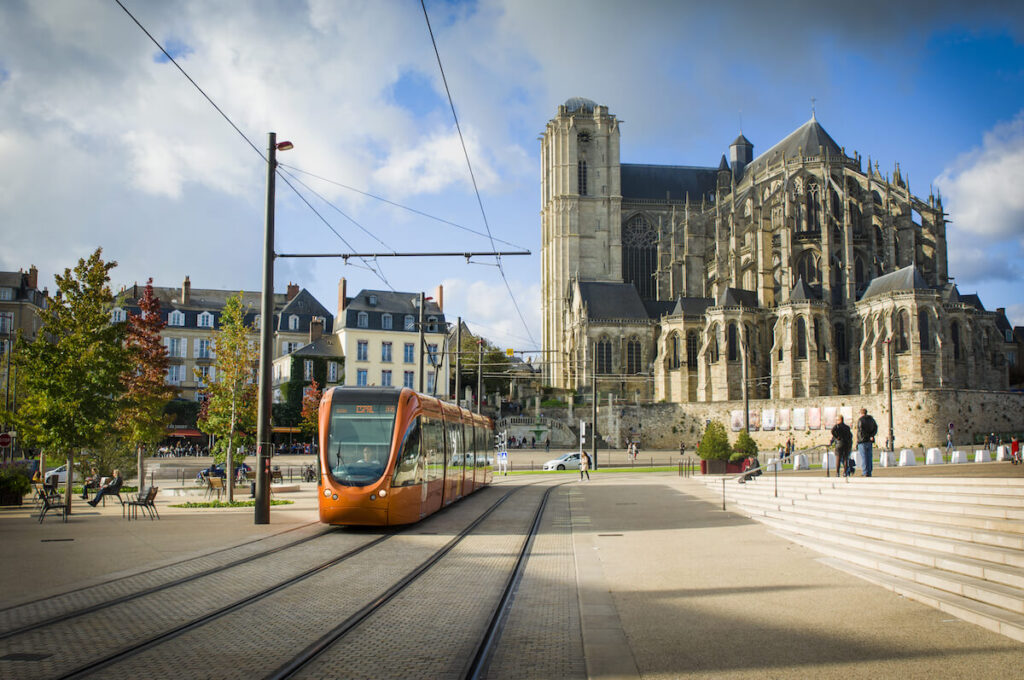 Roman cathedral of Saint Julien with an orange tram at a Le mans Sarthe, Pays de la Loire, France