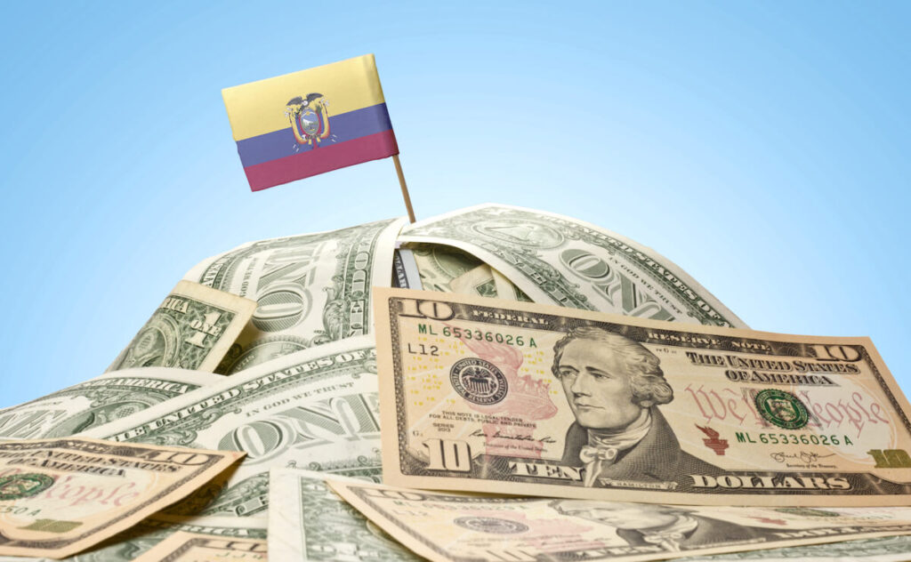 The national flag of Ecuador sticking in a pile of American dollars