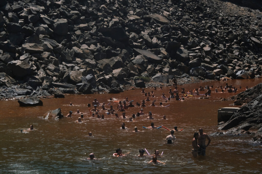 People enjoy the water of hot spring in the island of Santorini, Greece