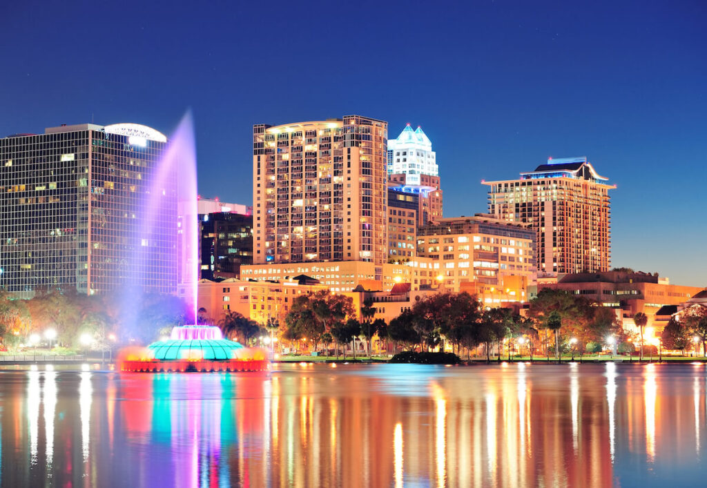 Orlando downtown skyline panorama over Lake Eola at night with urban skyscrapers, fountain and clear sky