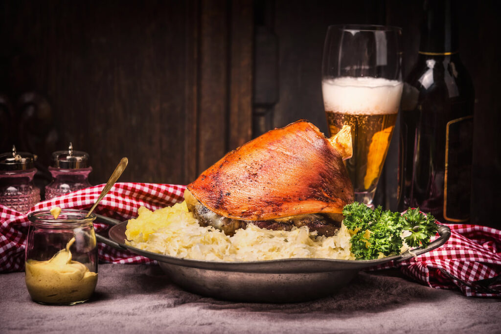 Roasted pork knuckle eisbein with mashed potatoes, braised pickled cabbage, beer and mustard