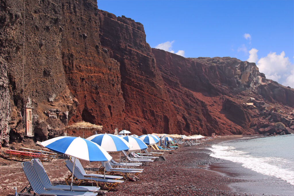 Row of deck chairs and umbrellas in the Red beach, Santorini, Greece