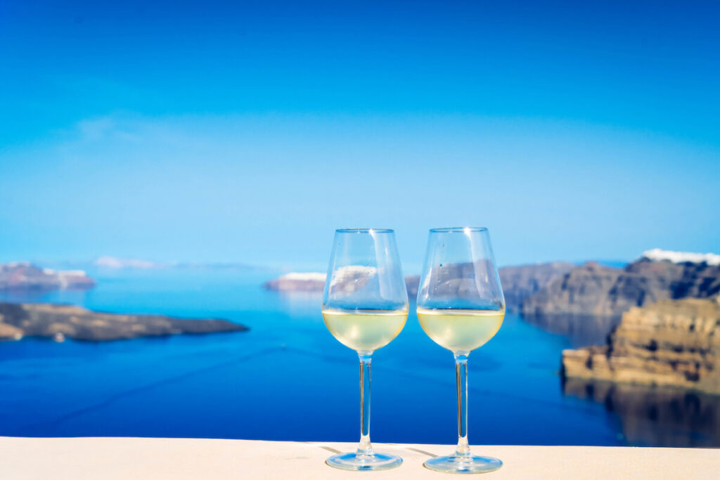 two glasses of white wine with Aegaen sea in background