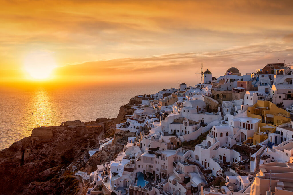 Golden summer sunset behind the picturesque village of Oia, at the edge of the caldera at Santorini