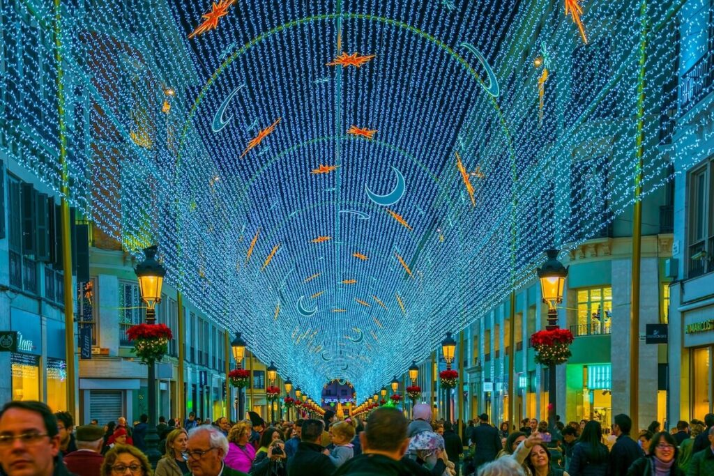 people are walking under christmas/new year decoration in shape of a light tunnel in the historical center of malaga