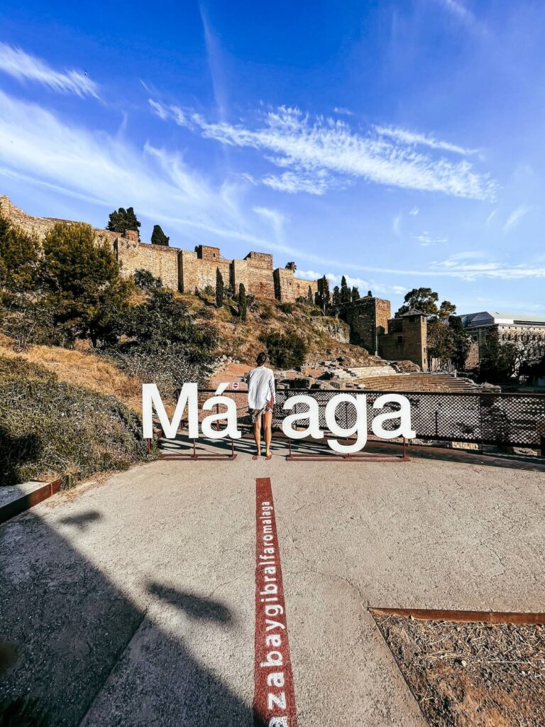 women standing beside a Malaga sign