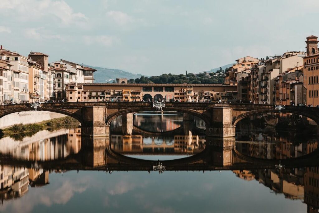 panoramic view of Ponte Vecchio in Florence with buildings and mountain in the background