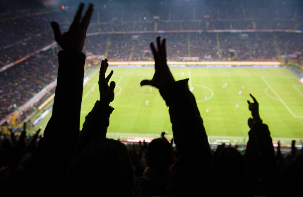 Crowd of football supporters and fans cheer at the stadium