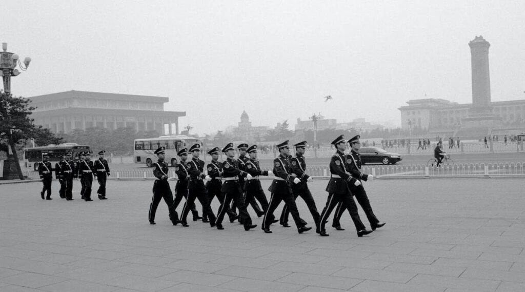 black and white photo of men marching in Tiananmen Square
