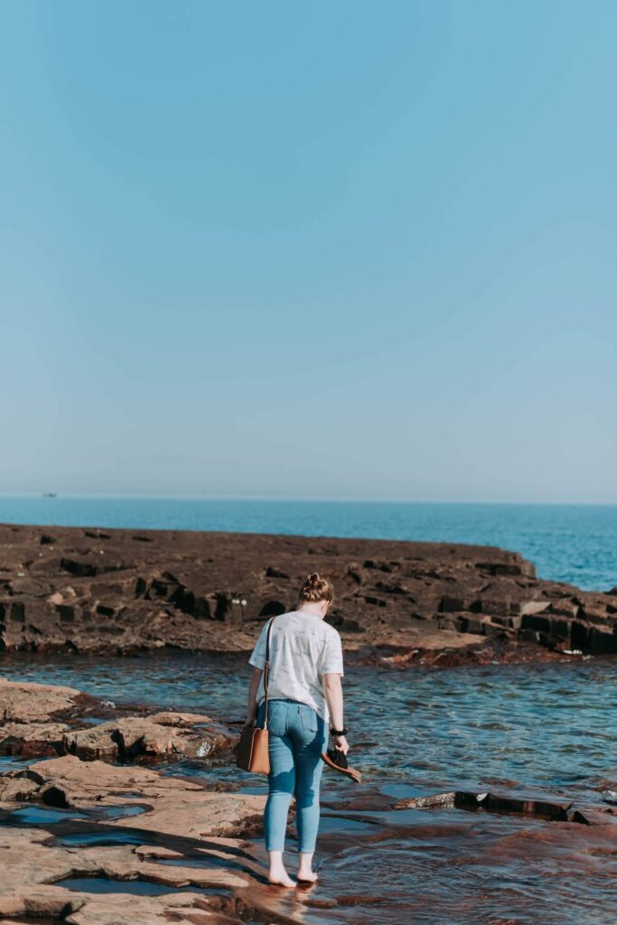 woman walking along the rocky edges of Grand Marais