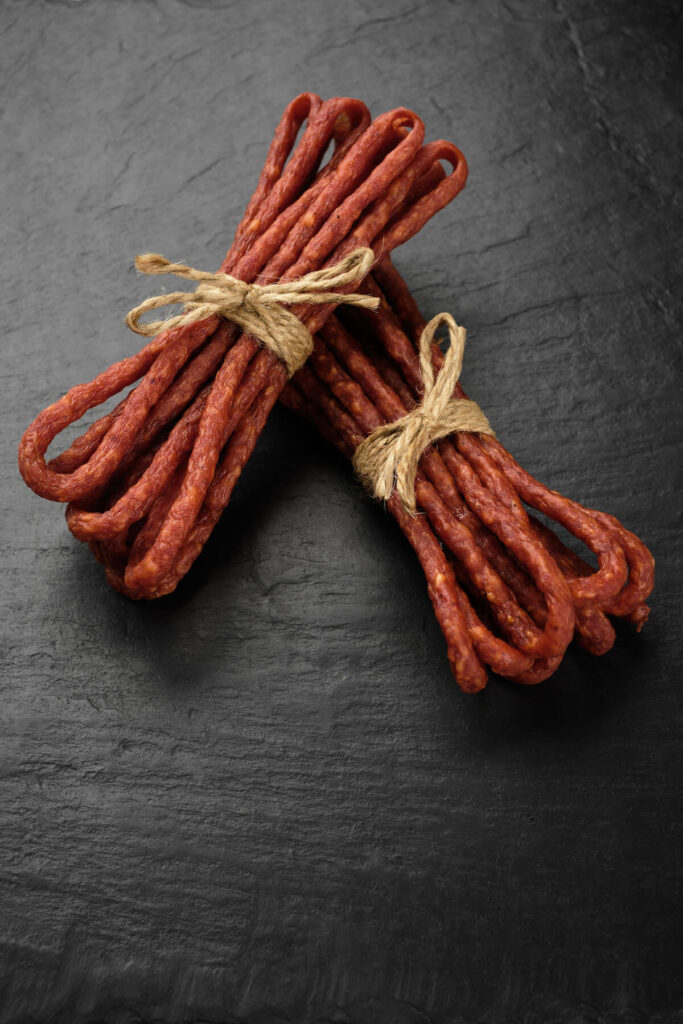 long and thin sausages kabanos on black background