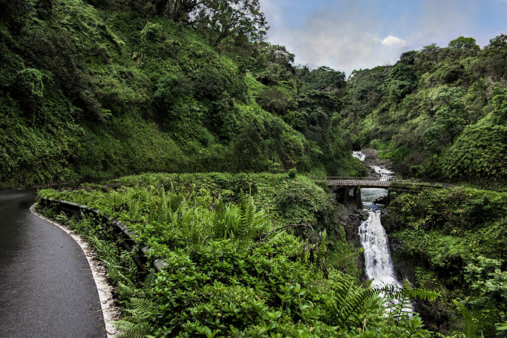 Road to Hana. The Hana Highway turns to cross a one lane bridge beside a waterfall on the north coast of Maui.
