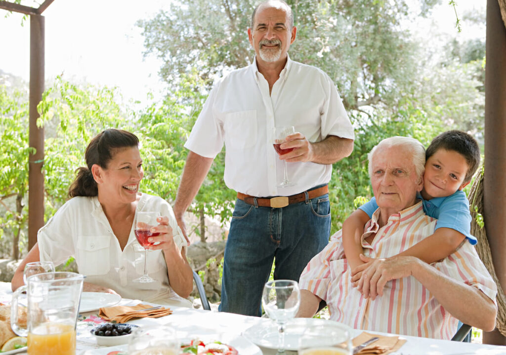 Group of joyful family members enjoying a Spanish tapas meal in a villa green garden while on a holiday in a summer home