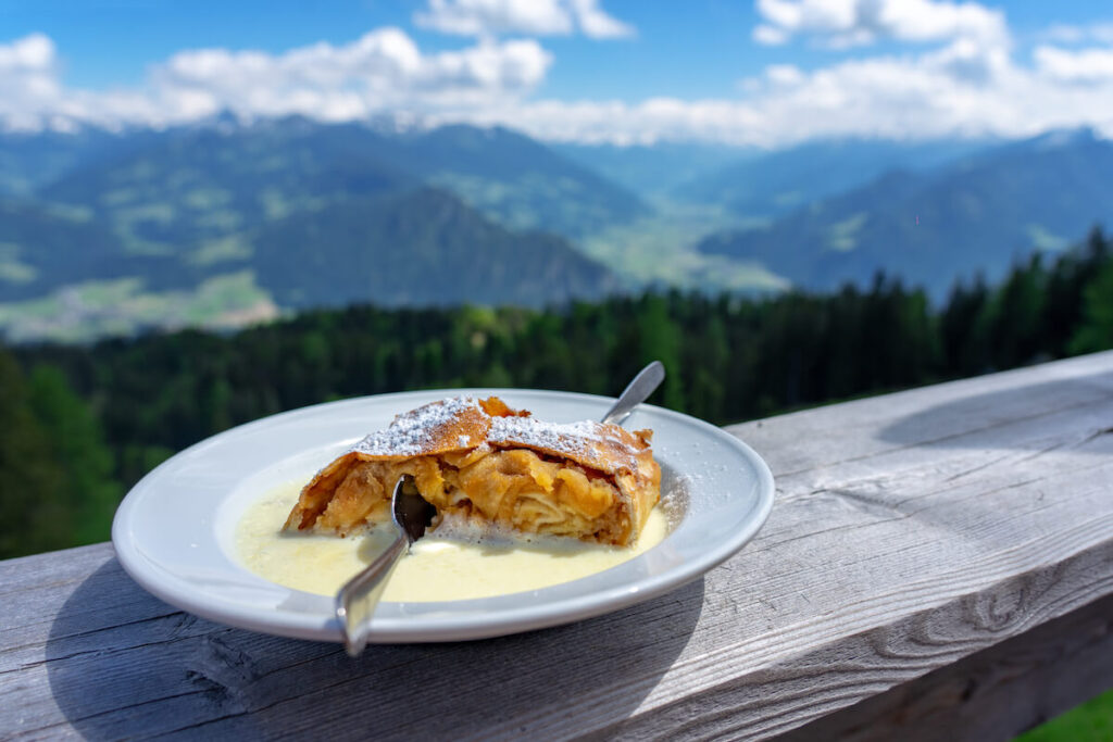 traditional apple strudel dessert with vanilla sauce in tirol alpine hut with mountain view. Salzburg is known for this dessert.