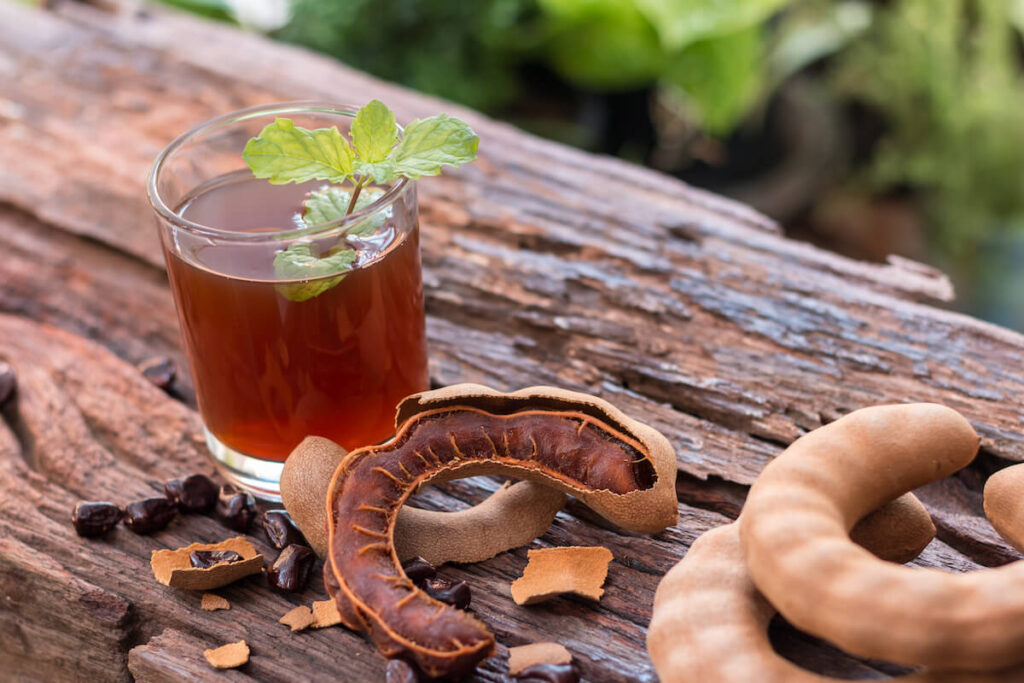 Delicious sweet drink tamarind, ripe tamarinds and seeds with mint leaves on rustic wooden table