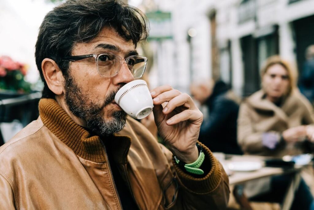 A handsome man sips an espresso at an outdoor table in Rome, Italy