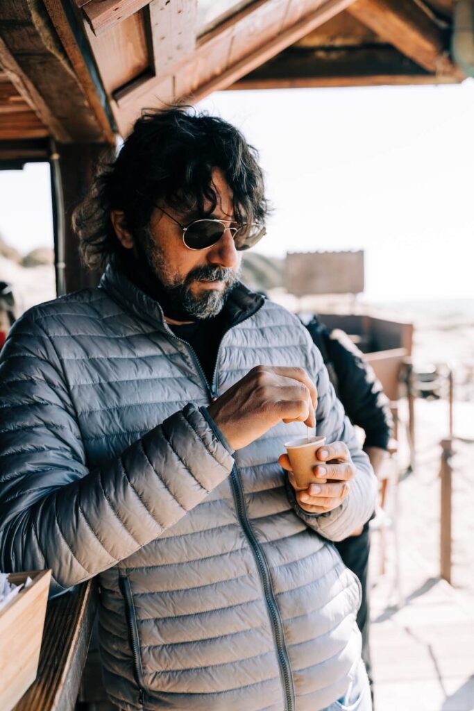 Italian man stirring a cup of espresso coffee leaning on the counter of a coffee shop at the beach