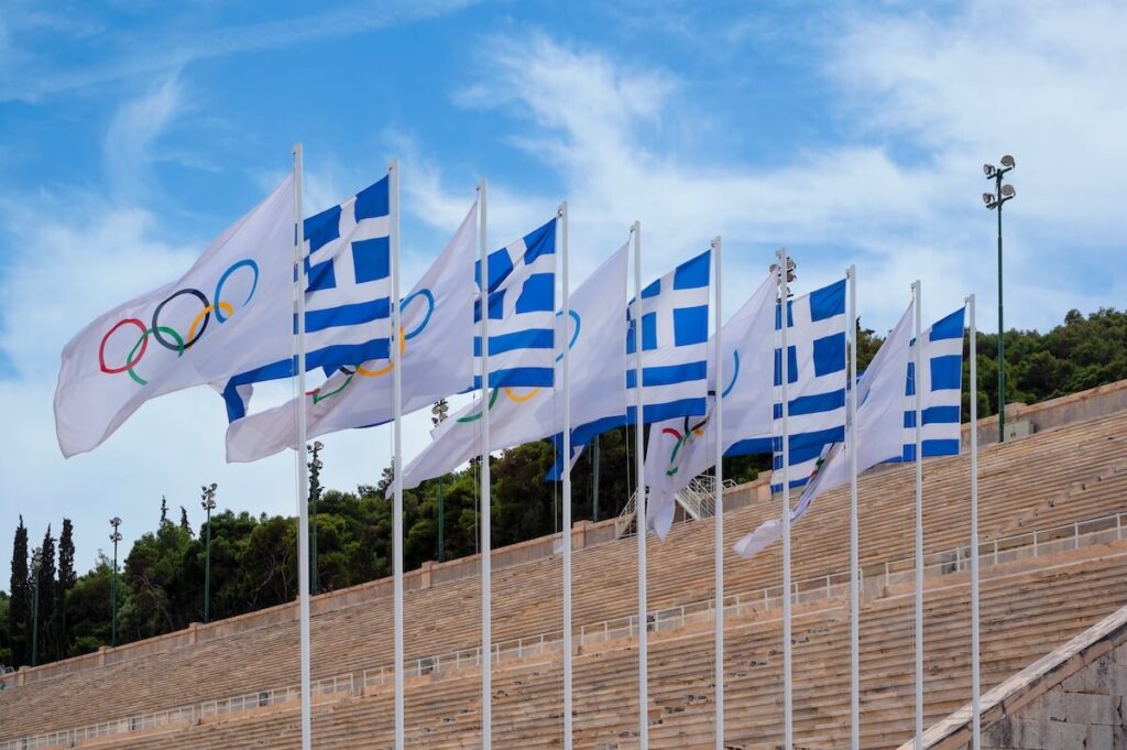 Waving Olympic flag and Greece flag captured at the first Olympic Panathenaic stadium at Athens, Greece