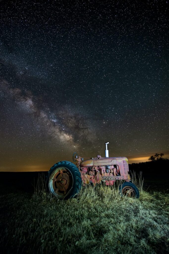 rustic old Farmall tractor sitting quietly on watch in rural Nebraska, gently watching as our Milky Way rolls overhead