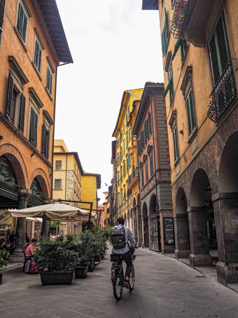 man biking along quiet street in Pisa