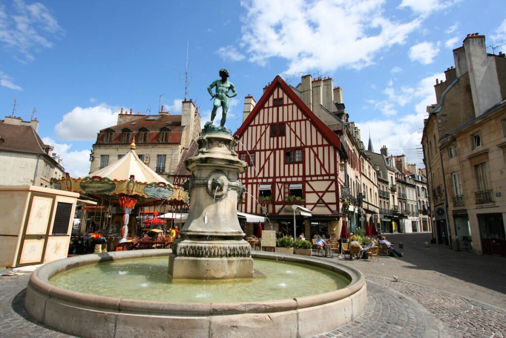 Famous fountain, characteristic houses and colorful carousel in Dijon, Burgundy, France