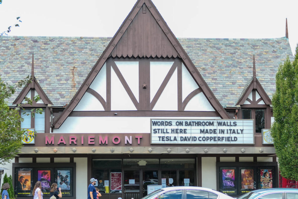 The historic Mariemont Theater has reopened and several people are walking down the street in front of the building.
