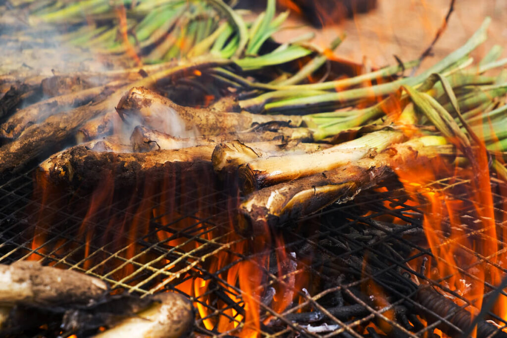 pile of calcots, sweet onions typical of Catalonia, Spain being cooked in the barbecue
