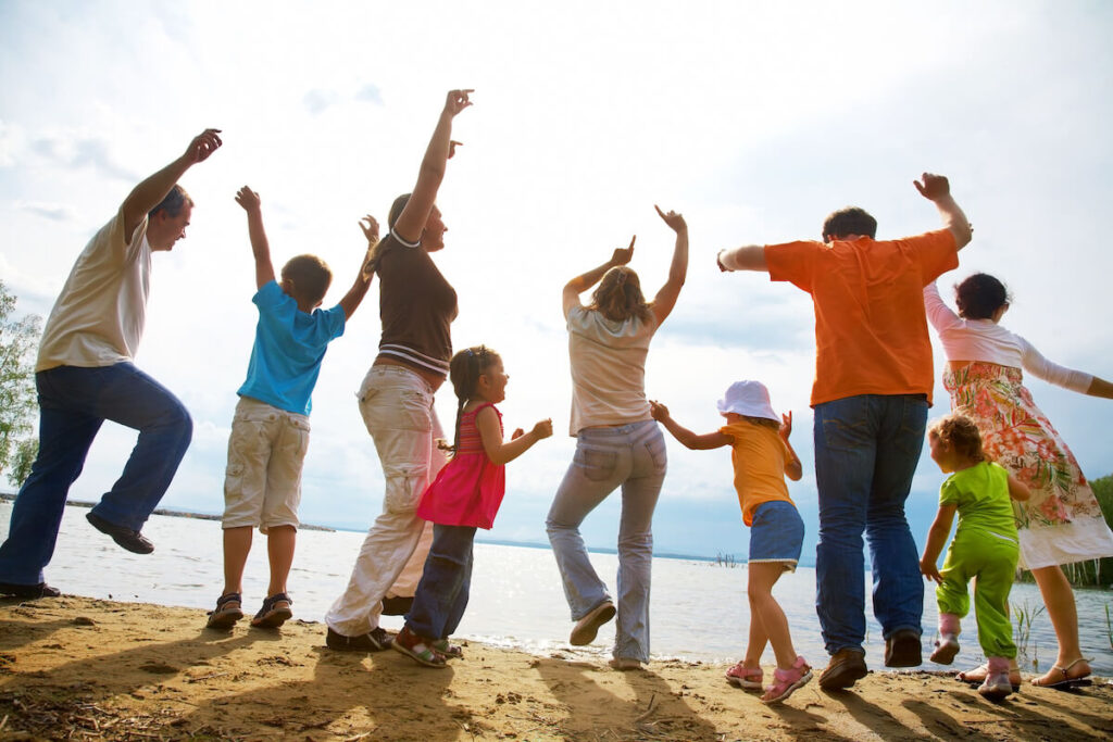 Big family from adults and children dancing on the beach