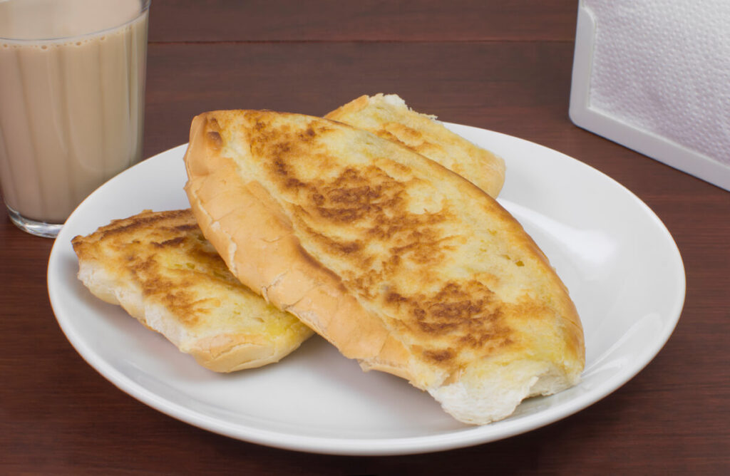 Popular Brazilian bread with melted butter called pão na chapa and a cup of hot coffee mixed with milk called média or pingado found in any bakery
