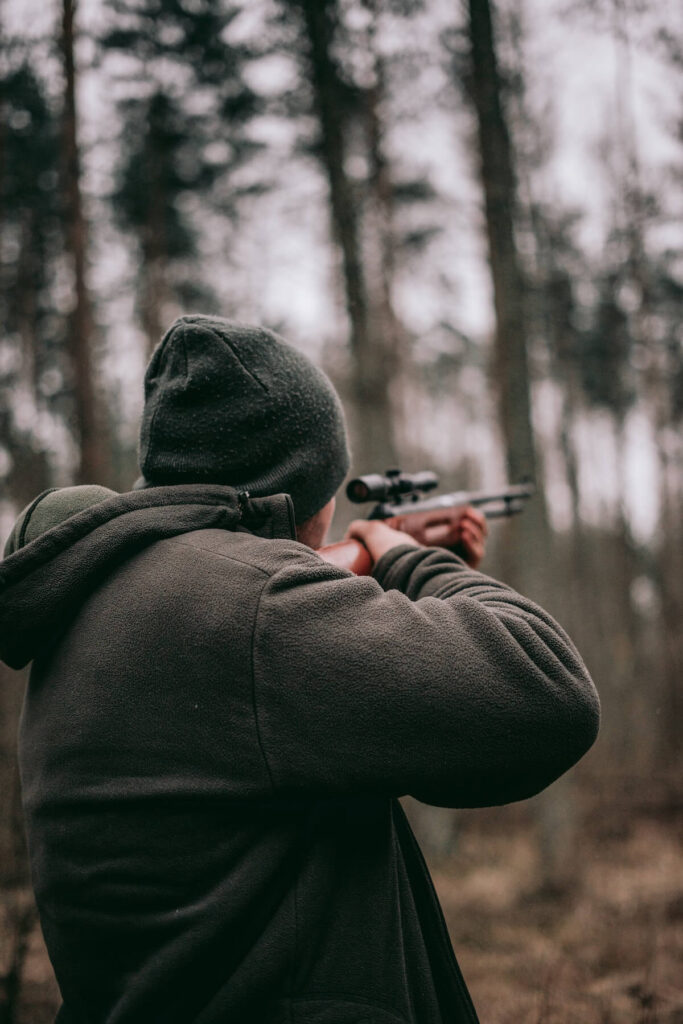 man shooting rifle in forest