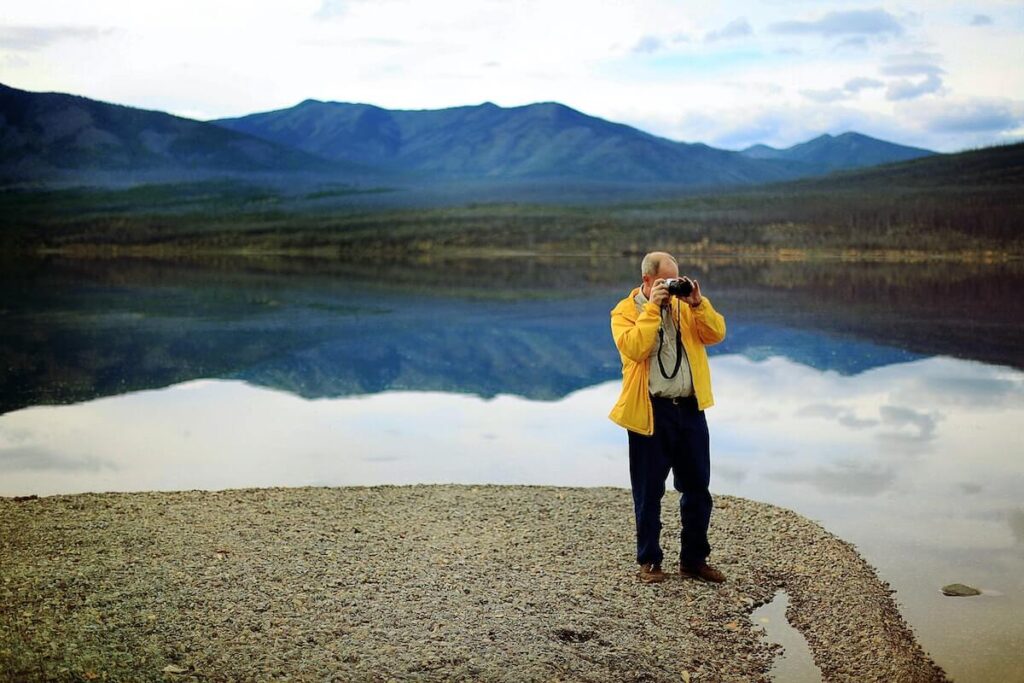 man takes photo on lake shore