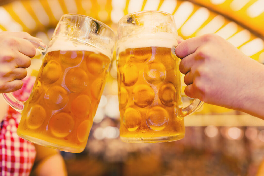 Two hands clinking beer glasses in Oktoberfest tent