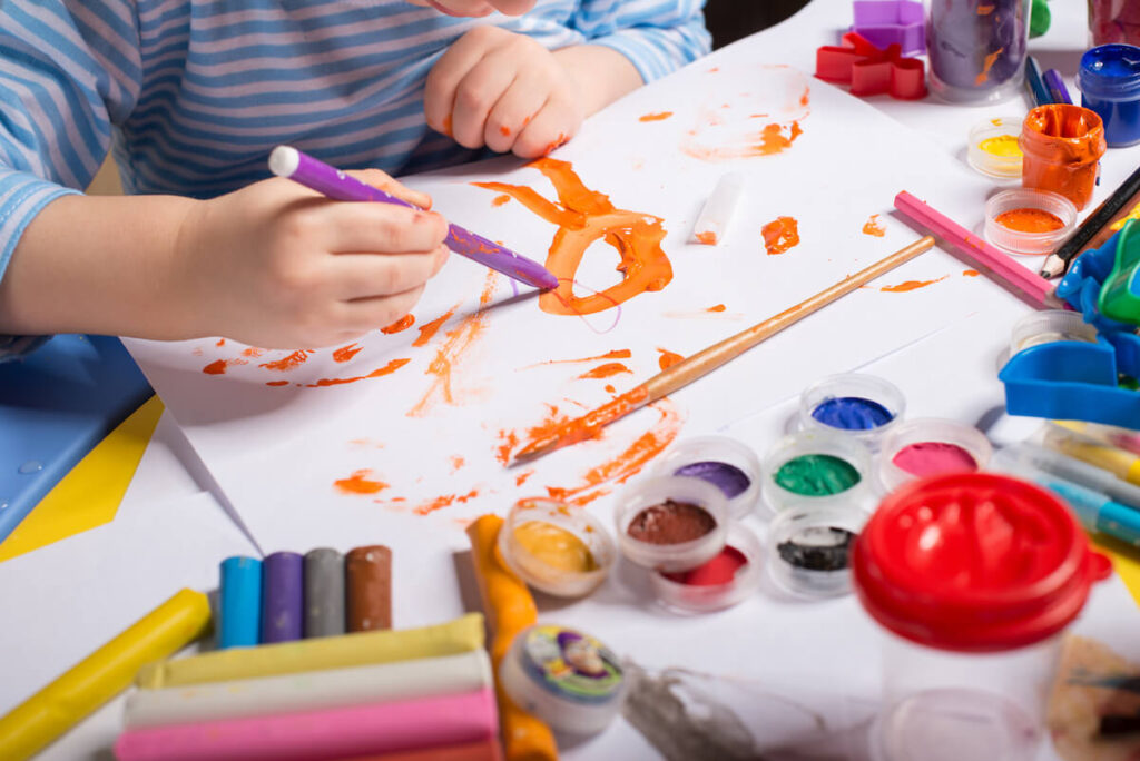 Boy painting hands during art lesson