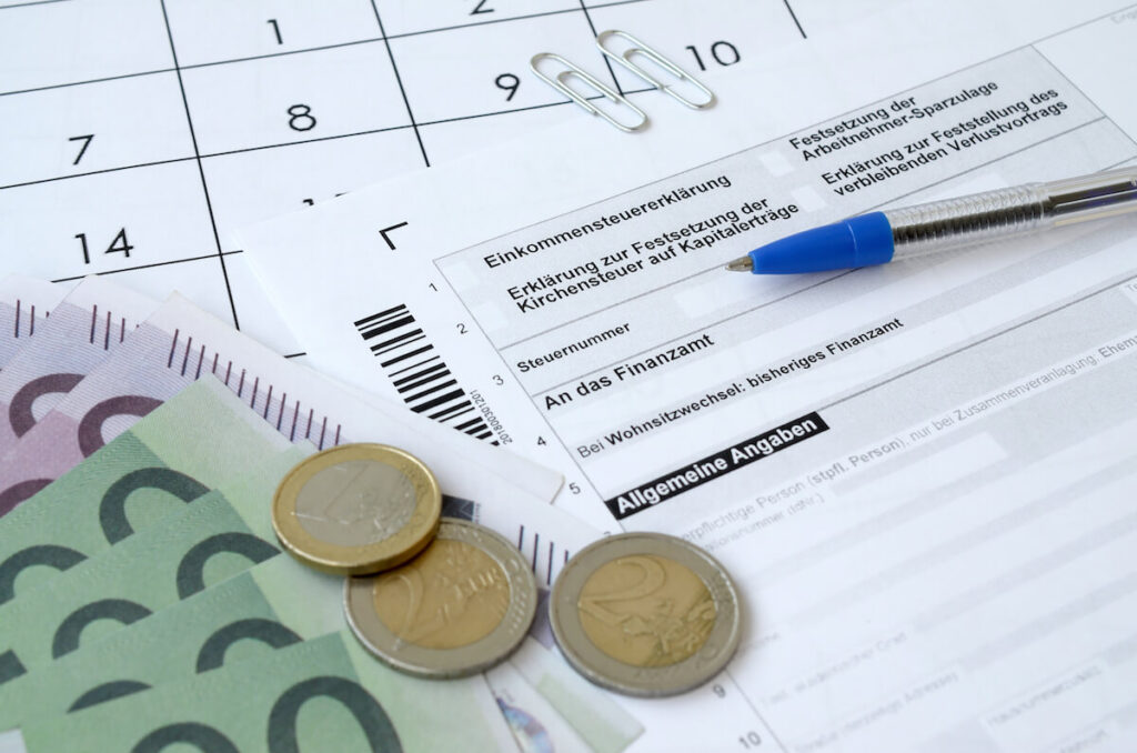 German tax form with pen and european money bills lies on office calendar