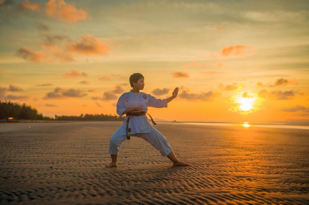 girl in martial arts uniform at a beach during sunset