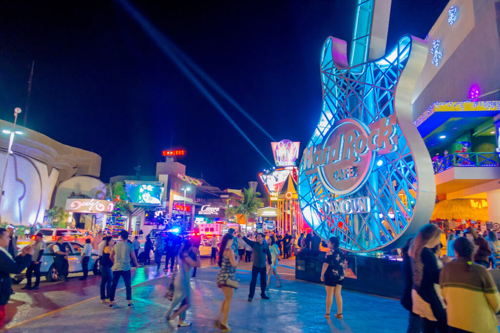 Crowd of people enjoying the night life at outdoors of Hard Rock Cafe in Cancun at the Forum center in Cancun's hotel zone