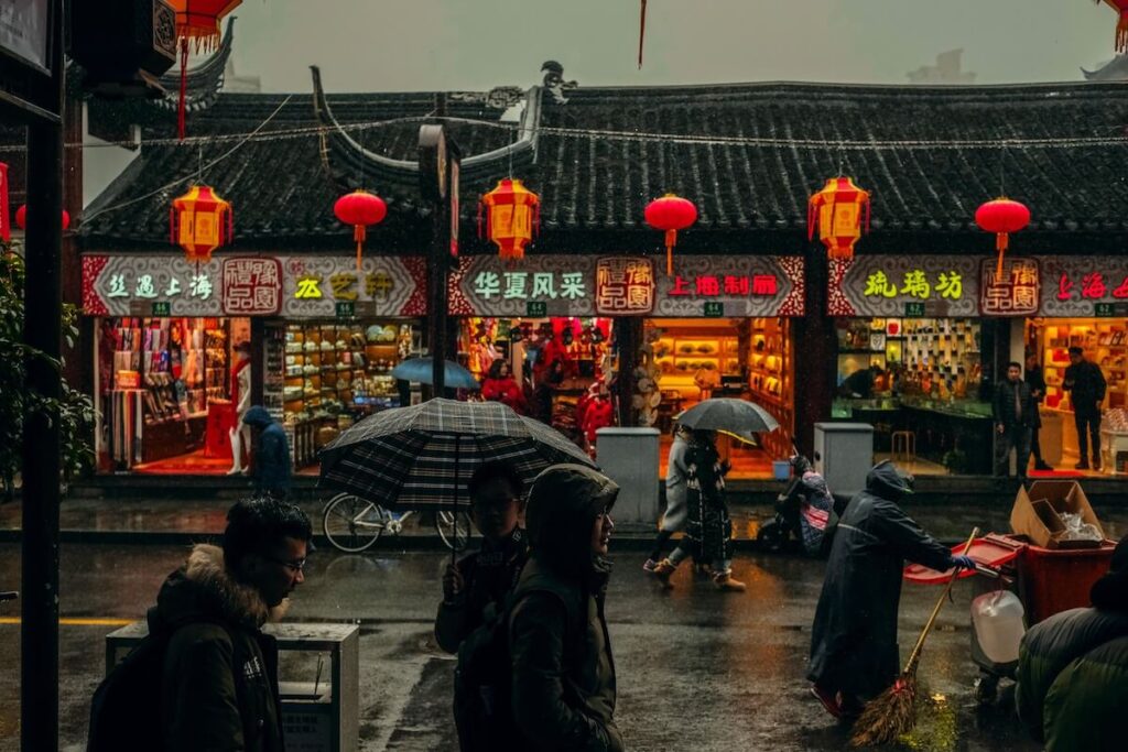 people walking with umbrellas along a street in Shanghai on a rainy day
